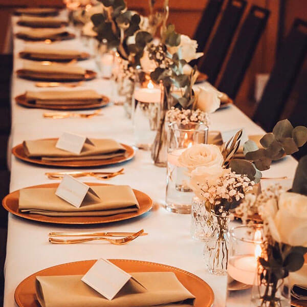 A long table set with elegant gold plates, representing wedding tableware rentals in Dallas, TX