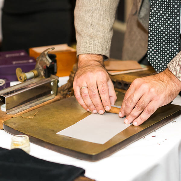 A man cuts paper while rolling traditional cigars from tobacco leaves in Dallas, TX